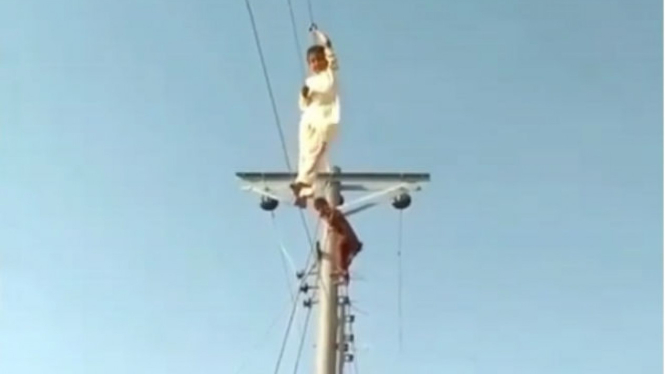 Anak bergelantungan di kabel listrik.