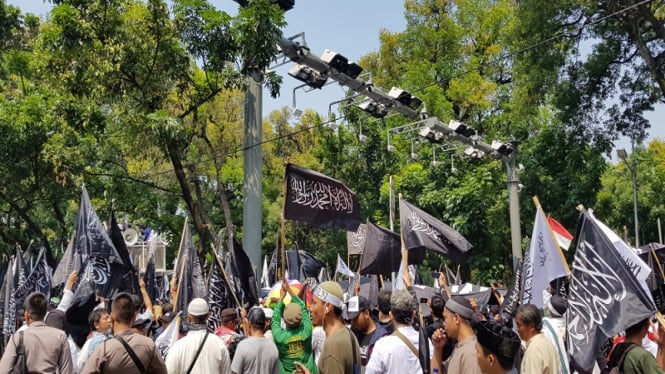 Massa mengibarkan bendera Tauhid di depan kantor Kemenko Polhukam 