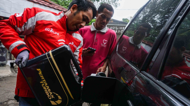 Runner (kedua kanan) melakukan pengisian bahan bakar minyak (BBM) untuk layanan Go Pertamina pada aplikasi GO-LIFE di Jakarta, 27 Oktober 2018.