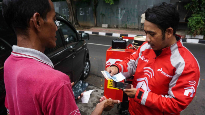 Runner (kanan) menerima pembayaran tunai atas pesanan bahan bakar minyak (BBM) untuk layanan Go Pertamina pada aplikasi GO-LIFE di Jakarta, 27 Oktober 2018.
