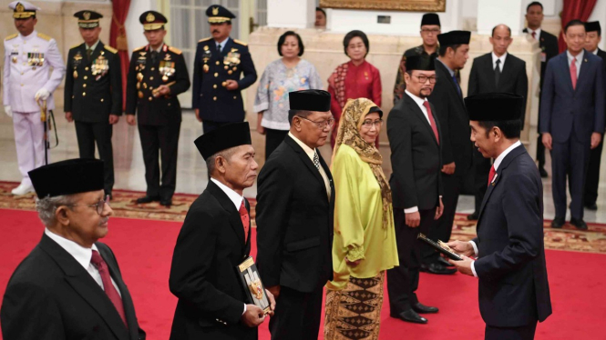 Presiden Joko Widodo (kanan) memberikan tanda jasa kepada ahli waris saat penganugerahan gelar pahlawan nasional di Istana Negara, Jakarta, Kamis, 8 November 2018.