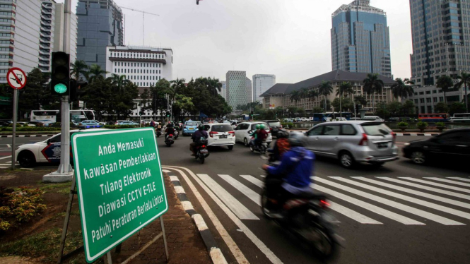 Pengendara melintas di dekat rambu tilang elektronik di Jalan Medan Merdeka Barat, Jakarta Pusat.