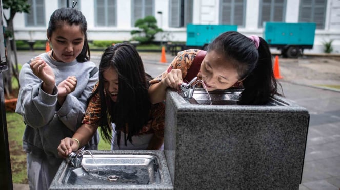 Pelajar mencoba fasilitas air minum langsung konsumsi yang tersedia di halaman Museum Nasional, Jakarta