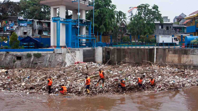 Petugas Dinas Kebersihan DKI Jakarta membersihkan sampah yang menumpuk di pintu air Manggarai, Jakarta, Senin, 12 November 2018.