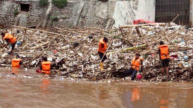 Petugas Dinas Kebersihan DKI Jakarta membersihkan sampah yang menumpuk di pintu air Manggarai, Jakarta.
