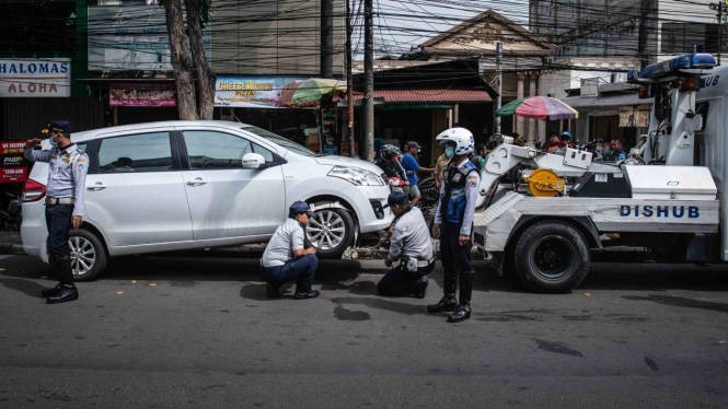 Petugas Dinas Perhubungan DKI Jakarta menderek mobil yang parkir sembarangan di Jalan Raya Mangga Besar, Jakarta