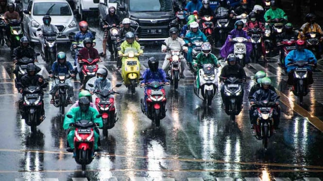 Pengendara sepeda motor menggunakan mantel saat hujan di kawasan Jalan MH Thamrin Jakarta beberapa waktu lalu.