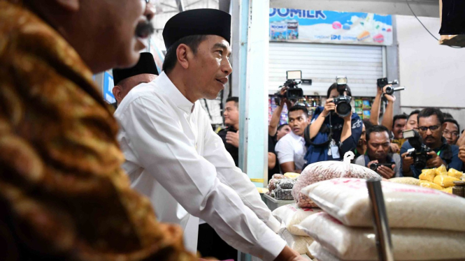Presiden Joko Widodo (kedua kiri) berdialog dengan pedagang di sebuah kios beras ketika mengunjungi Pasar Sidoarjo, Lamongan, Jawa Timur, Senin, 19 November 2018.