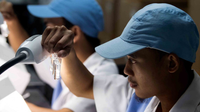 Petugas melakukan pemeriksaan visual vaksin manual sebelum pengemasan di laboratorium milik PT Bio Farma, Bandung, Jawa Barat
