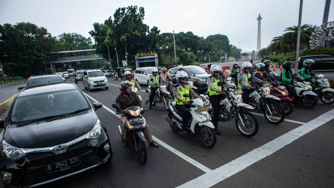 Sejumlah anggota Satlantas Polres Metro Jakarta Pusat saat melakukan sosialisasi tilang elektronik kepada masyarakat pengguna kendaraan bermotor di persimpangan Bundaran Patung Kuda, Jakarta