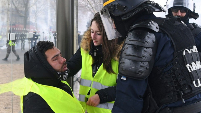 Seorang polisi dan pengunjuk rasa menolak peserta demonstrasi serta terkena semprotan gas air mata, Sabtu (01/12). - ALAIN JOCARD/Getty Images