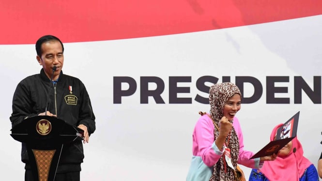 Presiden Joko Widodo (kiri) memberikan foto kepada penerima kartu Program Keluarga Harapan (PKH) saat sosialisasi di Gelanggang Remaja Jakarta Timur, Jakarta.