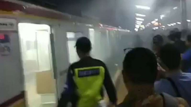Satu rangkaian kereta commuter atau KRL mengeluarkan asap pekat di perlintasan Stasiun Depok Lama pada Rabu 5 Desember 2018.