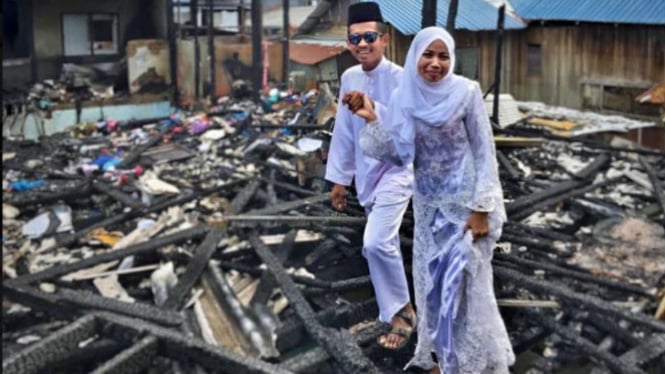 Pengantin berfoto di atas puing-puing rumahnya yang terbakar.