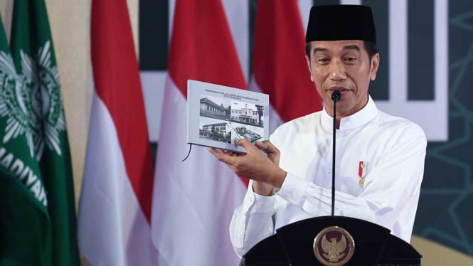 Presiden Joko Widodo menunjukkan buku ketika menghadiri milad satu abad Madrasah Muallimin dan Muallimat Muhammadiyah Yogyakarta di Yogyakarta