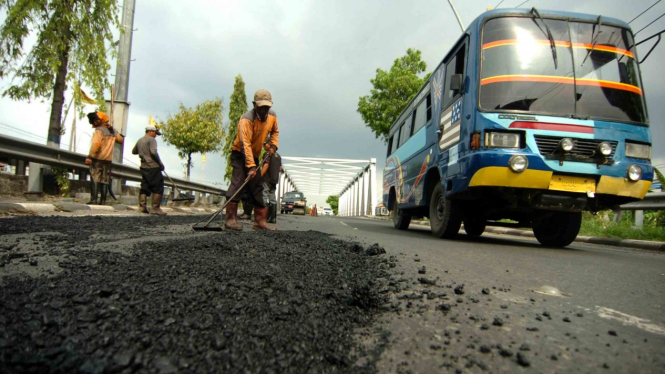 Pekerja mengerjakan pengaspalan jalan rusak di jalur Pantura Tegal, Jawa Tengah