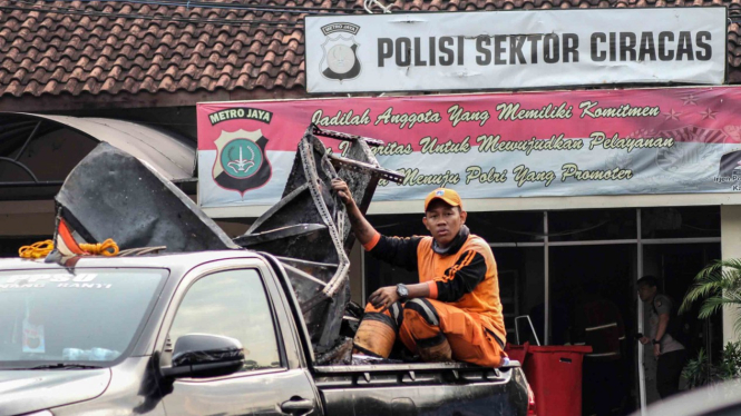 Petugas kebersihan mengangkut barang sisa perusakan dan pembakaran di Polsek Ciracas, Jakarta, Rabu, 12 Desember 2018.