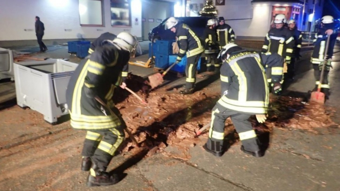 Petugas pemadam kebakaran berupaya menyendok cokelat yang sudah mengeras karena suhu dingin. - Reuters