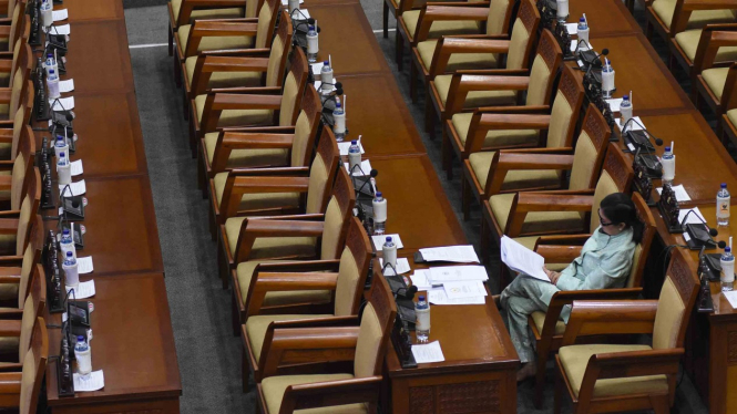 Seorang anggota DPR menghadiri Rapat Paripurna DPR di antara bangku yang tak terisi di Kompleks Parlemen, Senayan, Jakarta