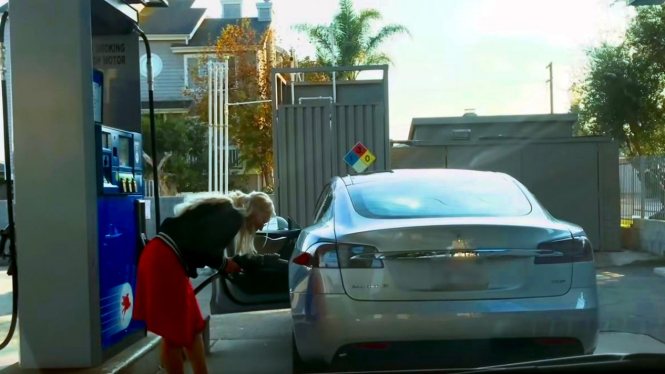 Wanita berambut pirang kebingungan saat hendak mengisi bensin ke mobil listrik.
