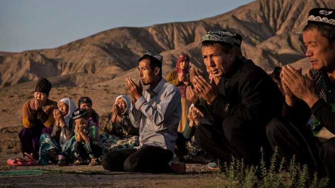 Keluarga Uighur berdoa di kuburan anggota keluarga mereka pada hari Idul Adha, September 2016, di wilayah Xinjiang barat. - Getty Images