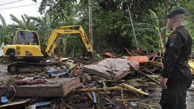 Petugas mengawasi operator alat berat membersihkan tumpukan sampah yang porak poranda menutupi jalan setelah diterjang tsunami di Pantai Carita, Pandeglang, Banten, Minggu, 23 Desember 2018.