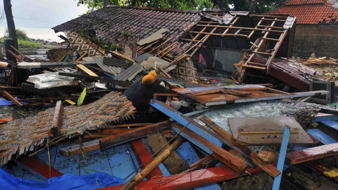 Warga menyelamatkan barang-barang miliknya dari reruntuhan rumah yang roboh dihantam tsunami di Kampung Pasawahan, Carita, Pandeglang, Banten