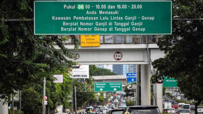 Kendaraan melintasi papan informasi penerapan sistem ganjil genap di Jalan Jenderal Gatot Subroto, Semanggi, Jakarta