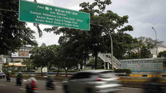 Kendaraan melintasi papan informasi penerapan sistem ganjil genap di Jalan Jenderal Gatot Subroto, Semanggi, Jakarta