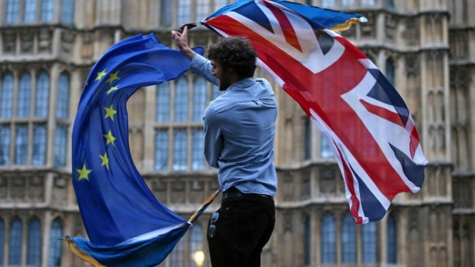 Seorang pria kibarkan bendera Uni Eropa dan Inggris.-AFP
