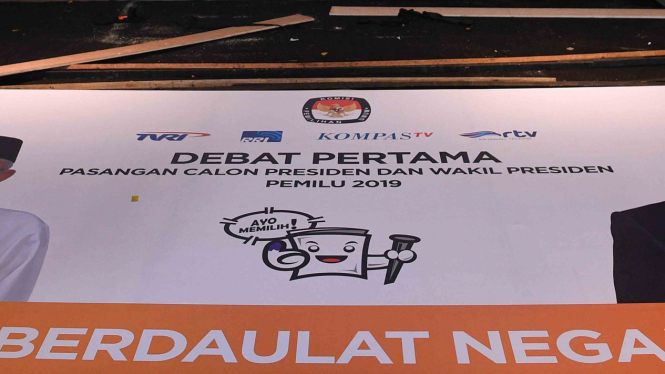 Petugas keamanan melintas di dekat spanduk yang dipersiapkan untuk debat pertama capres-cawapres Pilpres 2019 di Hotel Bidakara, Jakarta Selatan, Rabu, 16 Januari 2019.