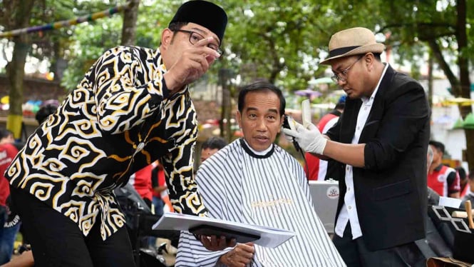 Presiden Joko Widodo (tengah) didampingi Gubernur Jawa Barat Ridwan Kamil (kiri) mengikuti potong rambut massal di area wisata Situ Bagendit, Garut, Jawa Barat