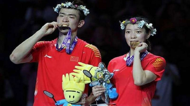 Zheng Siwei/Huang Yaqiong menggigit medali emas Kejuaraan Dunia 2018.