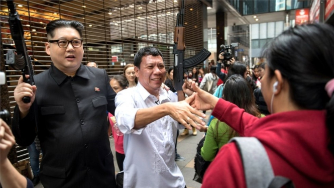 Dua pria ini mengacungkan senapan palsu, disambut oleh pelayanan dan anggota masyarakat saat mereka tiba di restoran ayam goreng di Hong Kong. - EPA