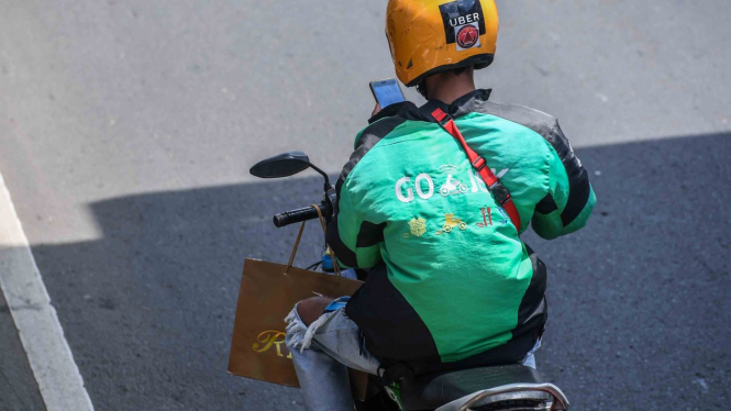 Pengendara sepeda motor mengamati aplikasi GPS (pelacak jalan) di gawainya saat berkendara di Jalan Rasuna Said, Kuningan, Jakarta, Kamis, 7 Februari 2019.