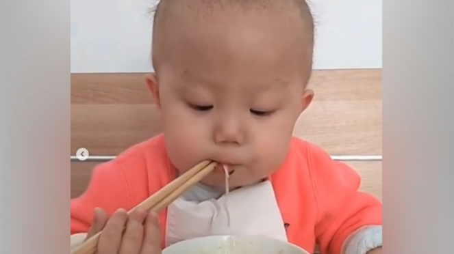 Bayi makan mi pakai sumpit.