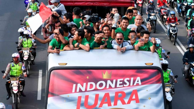 Pemain dan ofisial Timnas U-22 Indonesia menaiki bus tingkat ketika mengikuti konvoi menuju Istana Negara saat melintas di Jalan Sudirman, Jakarta, Kamis, 28 Februari 2019.