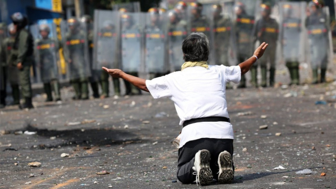 Seorang demonstran berlutut di hadapan pasukan keamanan di perbatasan Venezuela dan Kolombia -Reuters