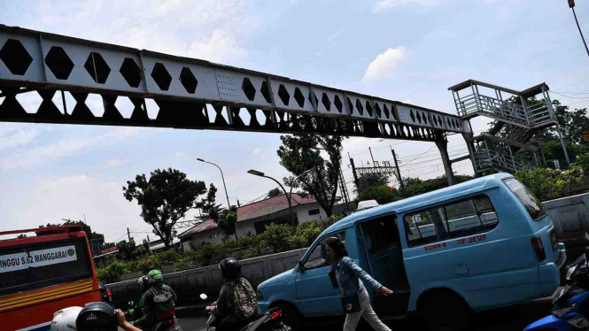 Warga dan pengendara motor melintas di dekat Jembatan Penyeberangan Orang (JPO) yang rusak di Pasar Minggu, Jakarta Selatan.