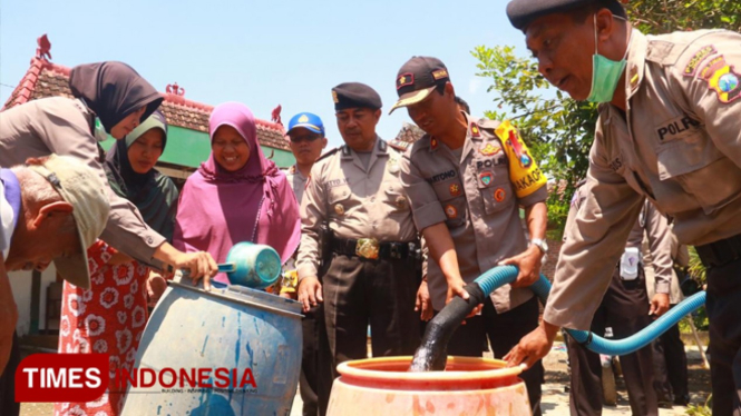 Anggota Polres Ngawi membantu warga membersihkan fasum dan menyalurkan air bersih di Â wilayah Kecamatan Kwadungan. (Foto: Ardian Febri TH/TimesIndonesia)
