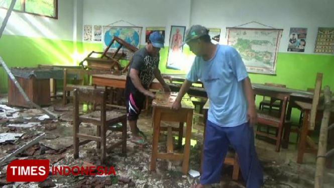 Warga sedang membantu bersih bersih serpihan genteng dan kayu di ruang kelas VI SDN Kedung Rejoso 2, yang hancur tertimpa pohon jati akibat puting beliung,(FOTO: Dicko W/TIMES Indoenasia)