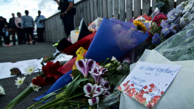 Petugas kepolisian berjaga didekat bunga yang diletakkan warga di depan Masjid Wellington, Kilbirnie, Wellington, Selandia Baru, Sabtu, 16 Maret 2019.