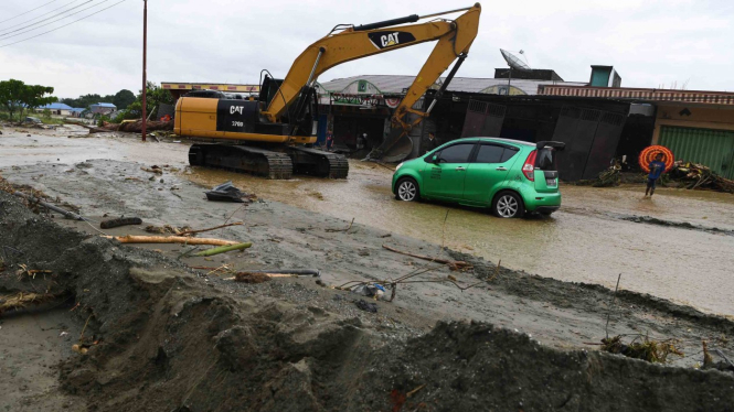 Sebuah alat berat mengevakuasi mobil yang terseret banjir bandang di Sentani, Jaya Pura, Papua, Senin, 18 Maret 2019.
