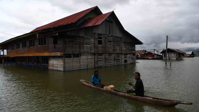 Warga menggunakan perahu melintas di samping gereja yang terendam banjir akibat meluapnya Danau Sentani dampak dari banjir bandang Sentani di Kampung Yoboi, Danau Sentani, Sentani, Jaya Pura, Papua, Jumat, 22 Maret 2019.