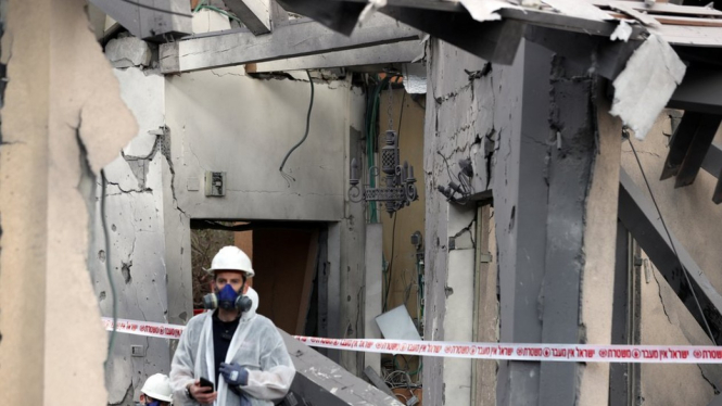 Seorang petugas kepolisian memerika rumah yang hancur karena dihantam roket di dekat Tel Aviv.-Reuters