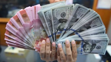 Pekerja menunjukkan uang rupiah dan dolar amerika serikat di sebuah tempat penukaran uang di jakarta