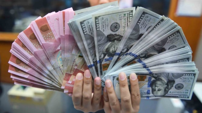 Pekerja menunjukkan uang Rupiah dan Dolar Amerika Serikat di sebuah tempat penukaran uang di Jakarta