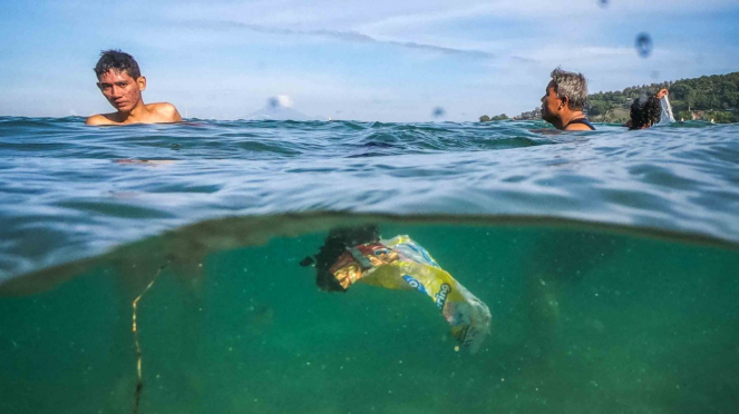 Sejumlah pengunjung berenang di dekat sampah plastik yang hanyut terbawa arus di pantai wisata Senggigi, Lombok Barat, NTB