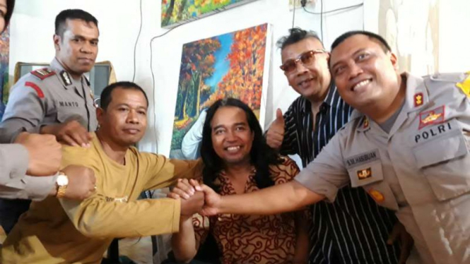 Seniman Slamet Jumiarto (tengah), warga nonmuslim yang ditolak oleh warga ketika pindah mukim di Kabupaten Bantul, saat bersama aparat Kepolisian usai mengadukan masalahnya pada Selasa, 2 April 2019.