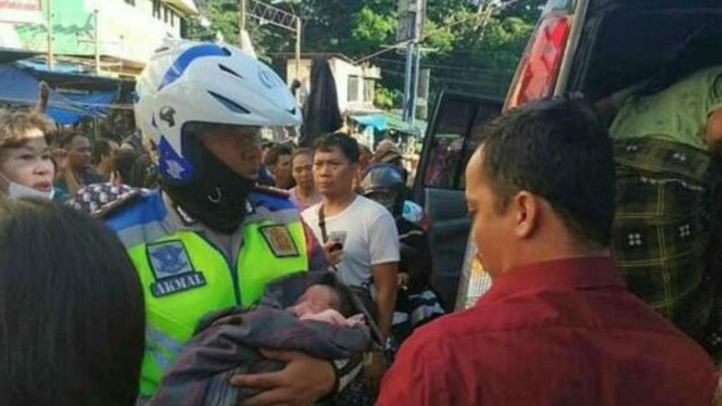 Polisi menggendong bayi yang dilahirkan di toilet di Pasar Bogor.